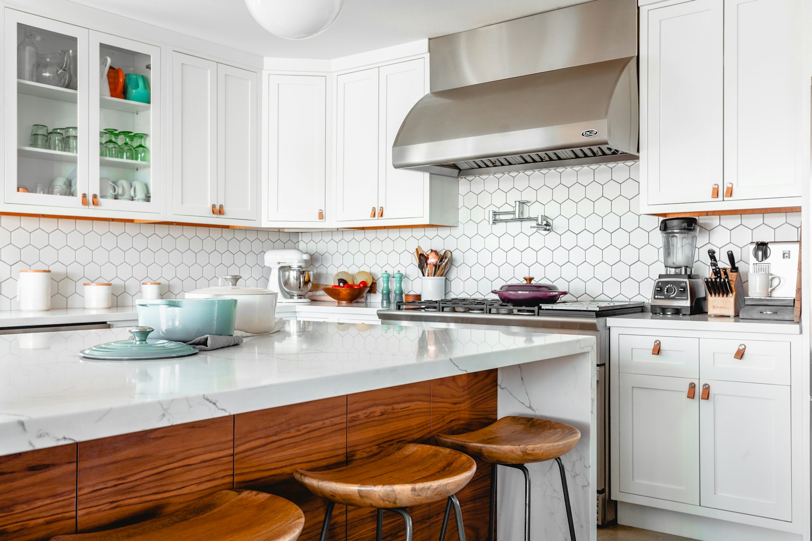 A white kitchen with stools arranged beside its counter